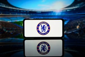 Chelsea Logo on Smartphone Against Stadium
