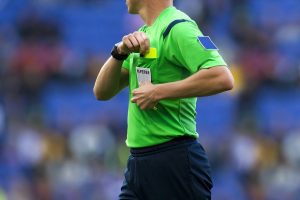 Referee in Green Taking Yellow Card Out of Pocket