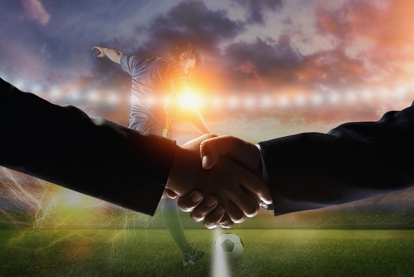 Handshake in Front of Footballer Kicking Ball