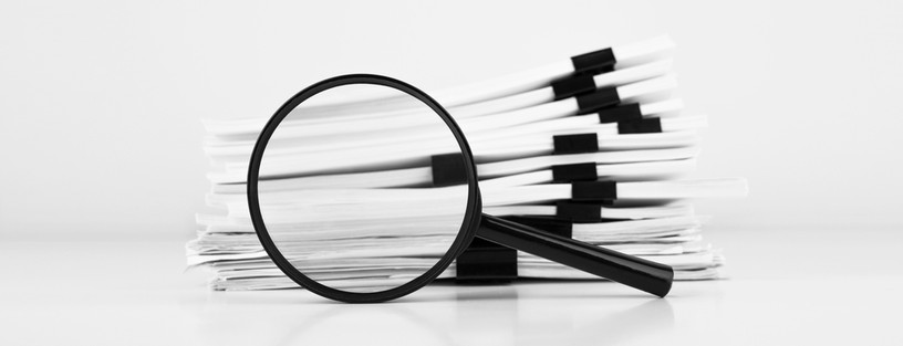 Stack of Documents with Black Magnifying Glass