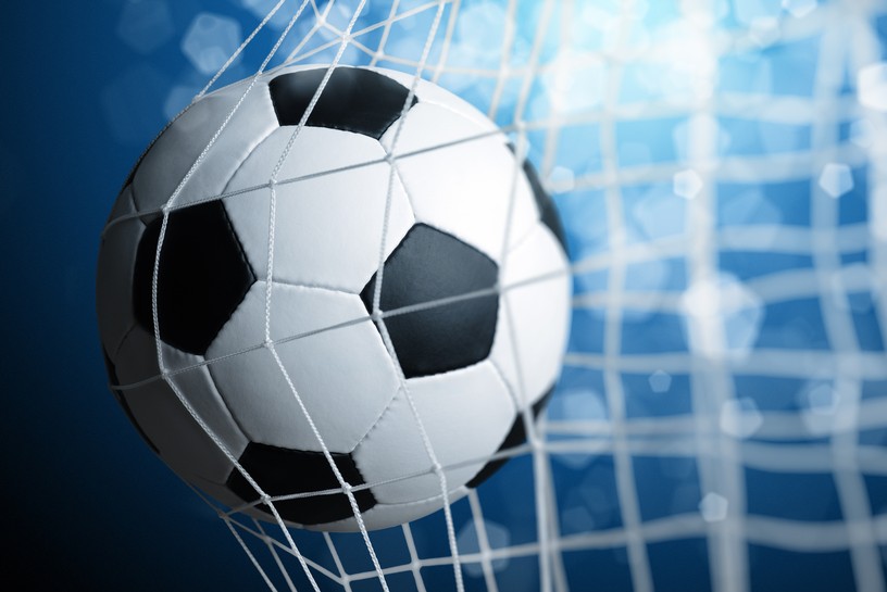 Football and Goal Net Close Up Against Blue Stadium Lights